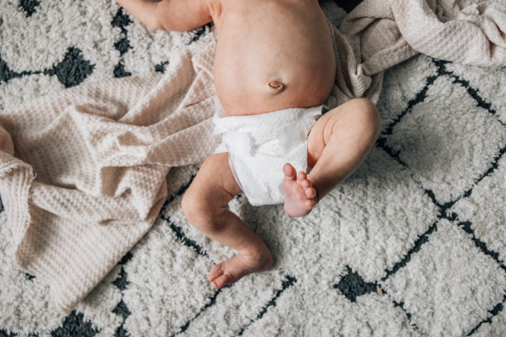newborn in diaper showing belly and legs